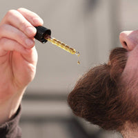 Person using a dropper to apply a liquid to their hair.